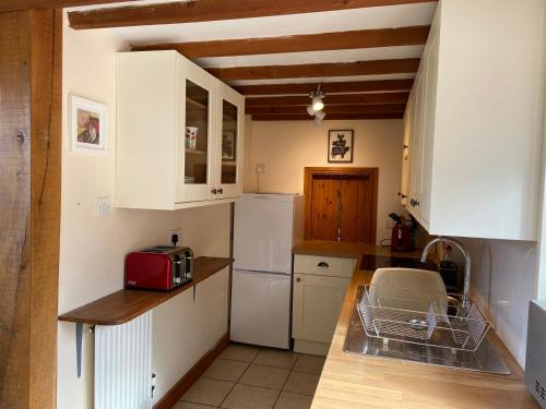 赛伦塞斯特Thames Cottage, Old Mill Farm, Cotswold Water Park的厨房配有白色橱柜和红色用具