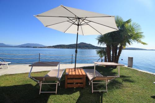 梅纳Resort Antico Verbano的两把椅子和一把雨伞在水边