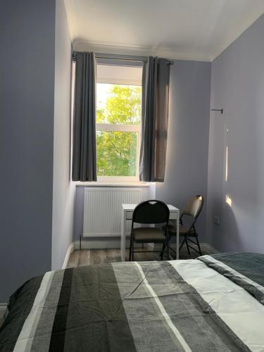 格拉斯哥Ibrox Argyll Sky Suite的一间卧室配有一张床、一张桌子和一个窗户。