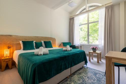 格但斯克Dom Zdrojowy的一间卧室配有一张带绿色床单的大床和窗户。