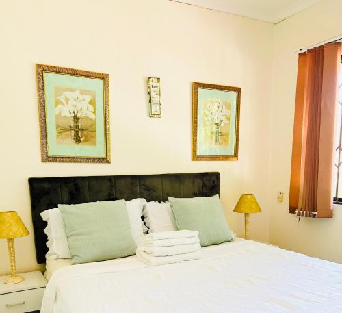 圣卢西亚23 St Lucia Sands的一间卧室配有一张带白色床单和两盏灯的床。