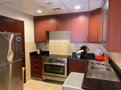 迪拜Lunar Hostel Plus的厨房配有木制橱柜和不锈钢冰箱。