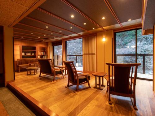 中之条Shima-Onsen Toshimaya的客厅配有椅子和桌子,设有窗户