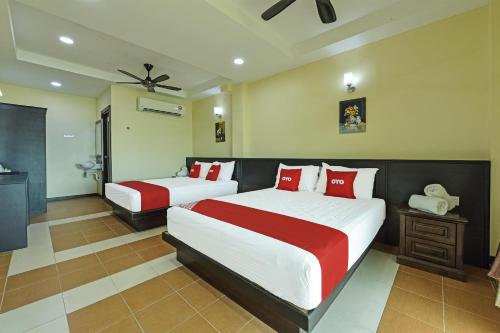 Super OYO Capital O 90656 Sera Sentosa Inn的一间卧室配有两张带红白色枕头的床