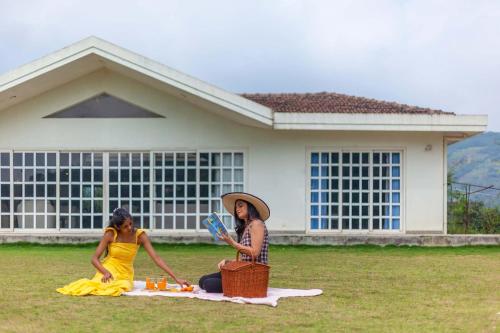 罗纳瓦拉StayVista's Shivom Villa 12 - A Serene Escape with Views of the Valley and Lake的两个女人坐在房子前面的草地上