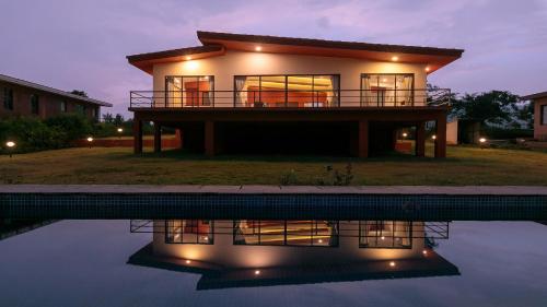 罗纳瓦拉StayVista's Shivom Villa 4 - A Serene Escape with Views of the Valley and Lake的水池中反射的房子