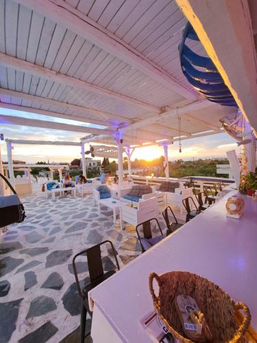 爱琴娜岛Naval Hotel Aegina的一个带白色桌椅的庭院,享有日落美景