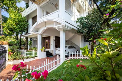 科钦Homested Homestay Fort Kochi的白色的房子,有白色的围栏和粉红色的花朵