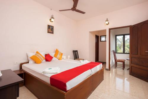 科钦Homested Homestay Fort Kochi的一间卧室配有一张大床,提供红色和黄色枕头