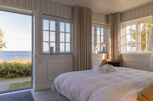 阿灵厄Allinge Badehotel的卧室设有一张大白色的床和大窗户