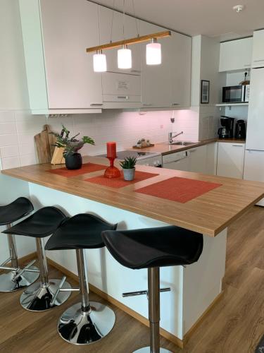 奥卢StarHomes Studio Lux 10的厨房配有白色橱柜和带凳子的木台面