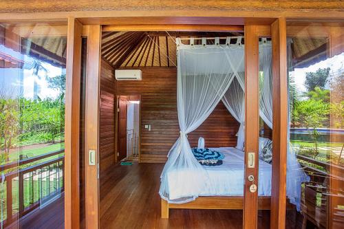 蓝梦岛Pondooks Joglo的一间卧室设有一张天蓬床和一个阳台