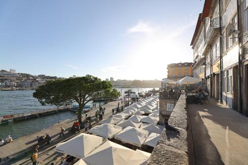 波尔图FLH Porto Ribeira with River View的水边人行道上的一排白色雨伞