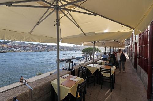 波尔图FLH Porto Ribeira with River View的河边餐厅,设有桌子和遮阳伞