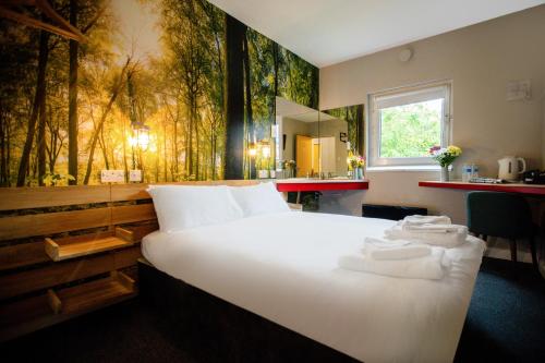 泰恩河畔纽卡斯尔梅德隆纽卡尔斯客栈的卧室配有白色大床和森林壁画