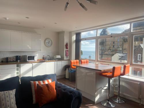 斯卡伯勒哈考特广场公寓的厨房配有带橙色椅子和柜台的岛屿