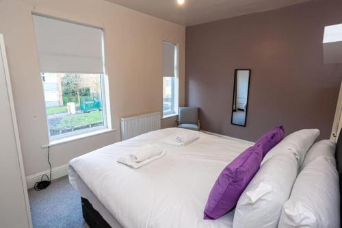 曼彻斯特Pillo Rooms - Spacious Cosy 2 Bedroom House by Bridgewater Canal的卧室配有一张带紫色枕头的大型白色床。