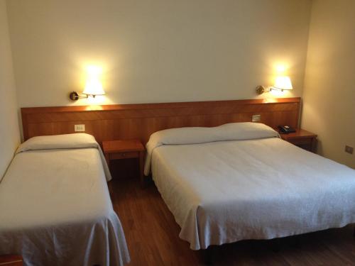 法诺克丽丝塔罗酒店的酒店客房设有两张床和两盏墙上的灯。