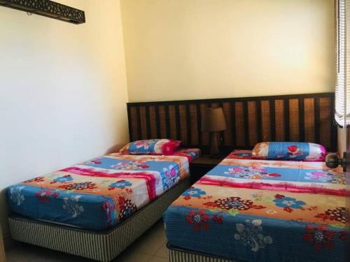 万津Gold Coast Morib Seaview 2 rooms Aircond Apartment的一间卧室配有两张带彩色床单的床