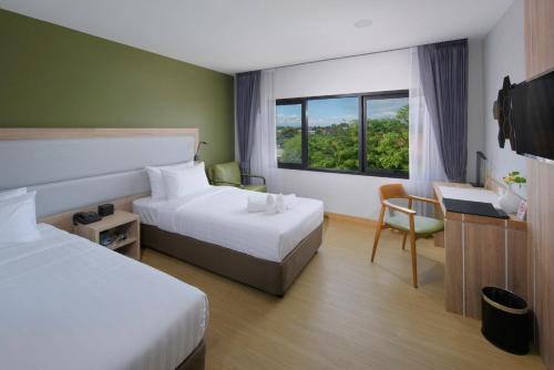 清迈Prime Square Hotel的酒店客房设有两张床、一张书桌和一个窗户。