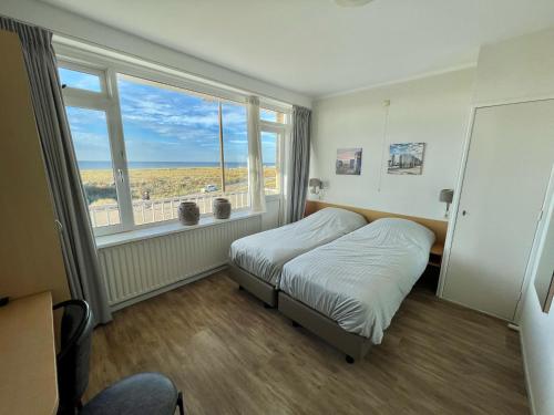 滨海卡特韦克Appartementen Zeezicht的一间卧室设有一张床和一个大窗户