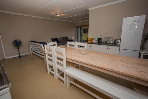 斯韦伦丹Appelsbosch Guest Farm的厨房配有长木桌子和白色椅子