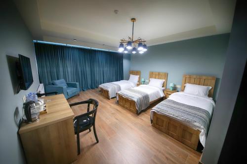 库塔伊西Hotel InnDigo in Kutaisi的酒店客房设有两张床、一张桌子和一张桌子。