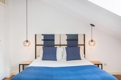 里斯本Stunning and Spacious Lofts just by Graça and Alfama的一间卧室配有蓝色和白色的床,配有两盏灯