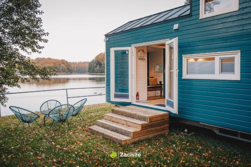 普日维兹Półwysep Zacisze - Tiny House Village的蓝色的房子,设有楼梯和两把椅子,还有门