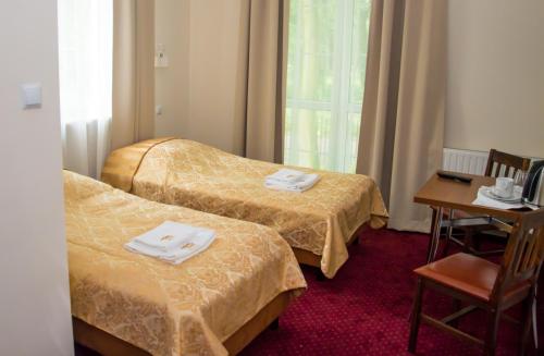 马佐夫舍地区新庄园莫德林宫酒店的酒店客房,设有两张床和一张桌子及椅子