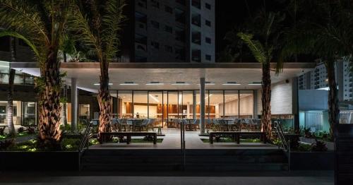萨利诺波利斯Salinas Premium Resort的一座晚上有两把长椅和棕榈树的建筑