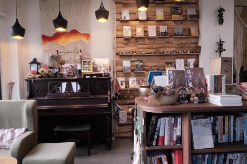 Hu-hsia舊事民宿 Old things in quemoy的图书馆配有钢琴和桌子,备有书籍