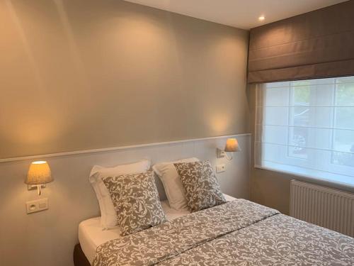 韦姆Les Rhododendrons的一间卧室配有带两个枕头的床和窗户