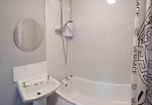 诺丁汉Cheerful 3 Bedroom Apartment的白色的浴室设有水槽、浴缸和镜子