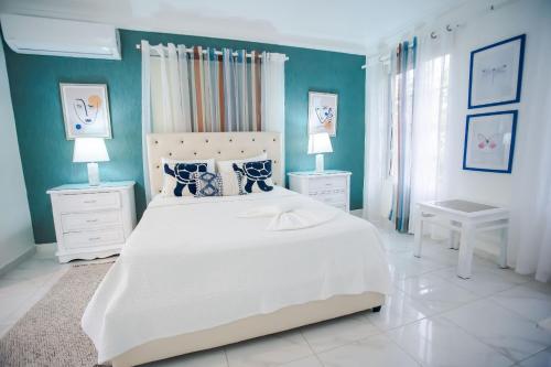 ParaísoVilla impecable con piscina privada en Juan Dolio的卧室配有白色大床和蓝色的墙壁