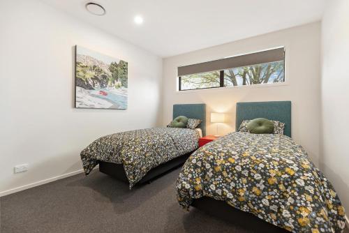箭镇Luxe Arrowtown Home的一间卧室设有两张床和窗户。