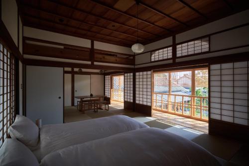 仓敷滔々 倉敷民藝館南の宿 toutou, Mingeikan Minami no Yado的卧室配有床、桌子和窗户。