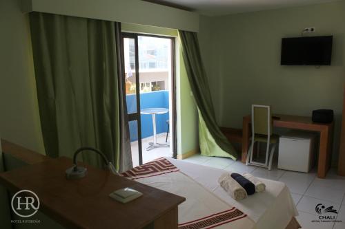 普拉亚Hotel Roterdão "Under New Management"的一间卧室配有一张床、一张桌子和一个窗户。