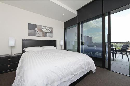 堪培拉堪培拉市堪培拉公寓的一间带一张白色大床的卧室和一个阳台