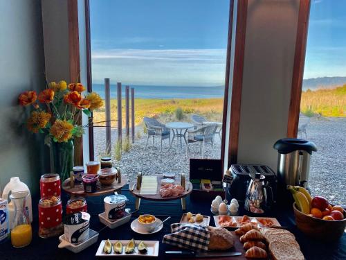 TuatapereThe Cliffs Seaside Lodge的一张带食物的桌子,享有海滩美景