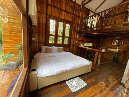 Ban Don KlangBaanraipoonwana Baanboonmak的木制客房内的一间卧室,配有一张床