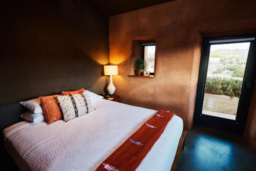 约书亚树Sacred Sands的卧室配有带枕头的床铺和窗户。