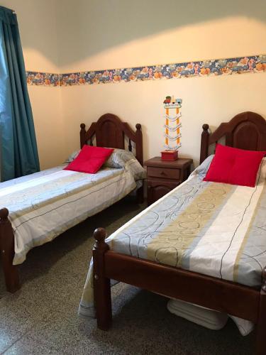 蒂诺加斯塔Urqu-Pacha Alojamiento的一间卧室配有两张带红色枕头的床。