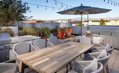 洛杉矶Modern Apartment Rentals的露台上配有一张木桌和椅子,配有遮阳伞