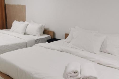 阿罗士打Tang Hotel的配有2张床的带白色床单和枕头的客房