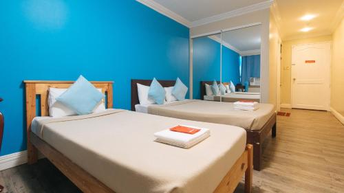 马尼拉RedDoorz @ Manila Airport Hotel的蓝色墙壁客房的两张床
