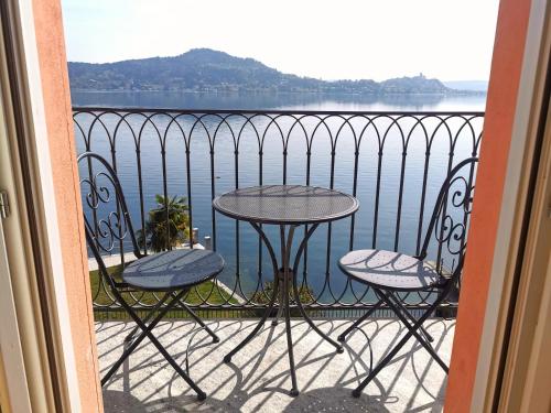 梅纳Resort Antico Verbano的阳台配有桌椅,享有水景