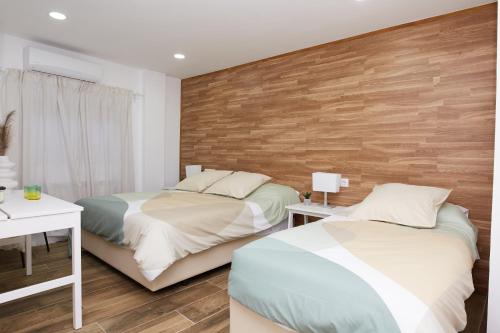 El CuervoEl Hortal i lloo的一间卧室设有两张床和木墙