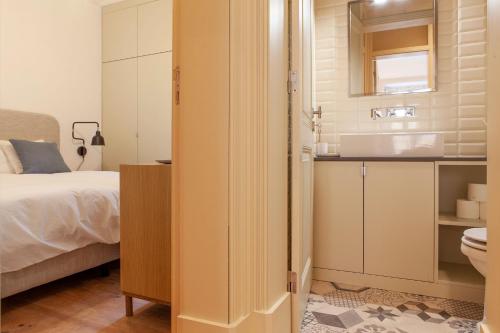 里斯本Charming 2BDR Apartment in Lapa by LovelyStay的一间卧室配有一张床,浴室设有水槽