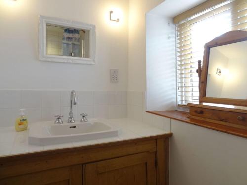 比明斯特Fiddlesticks Cottage的一间带水槽和镜子的浴室以及窗户。